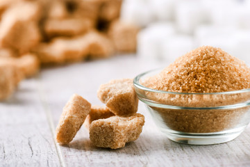 Brown sugar cubes on white rustic table. Brown sugar in glass bowl.