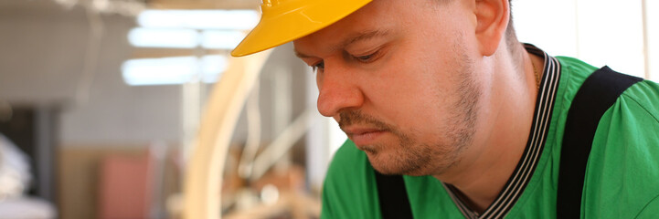 Obraz premium Portrait of young attractive man in work clothes and yellow helmet crossed arms smiling at shop for manufacturing furniture and details home interior