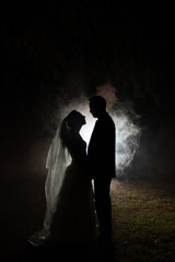 silhouette of a bride and groom at night with a smokey background