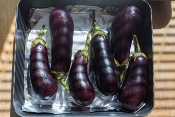 Whole eggplants prepared for baking on oven tray, top view