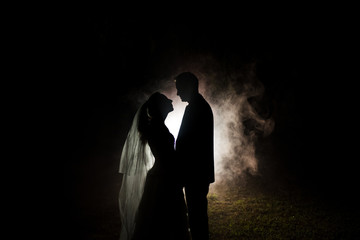 silhouette of a bride and groom at night with a smokey background