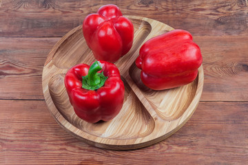 Red bell peppers on wooden serving dish on rustic table