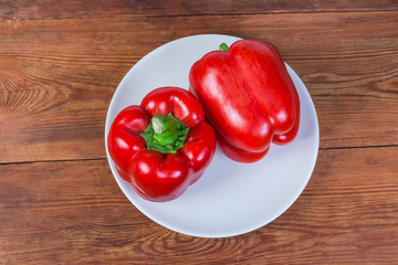 Top view of two fresh red bell peppers on dish