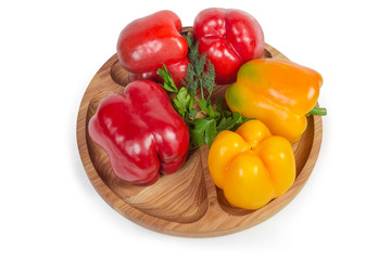 Red and yellow bell peppers, greens on wooden compartment dish
