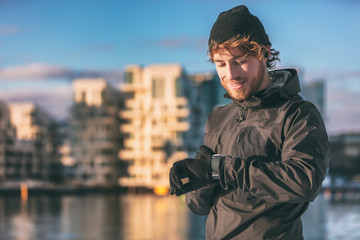 Smartwatch runner athlete man looking at his wearable technology smart watch on morning outdoor run...