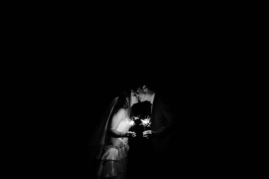 bride and groom kissing holding sparklers on their wedding day