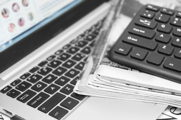 Newspapers and laptop. Pile of daily papers with news on the computer. Pages with headlines, articles folded and stacked on keypad of electronic device. Modern gadget and old journals, focus on paper 