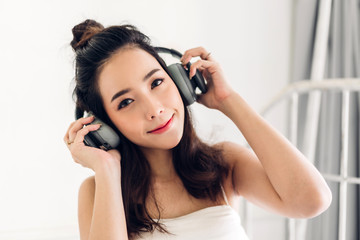 Fototapeta premium Beautiful young asia woman relaxing listening to music with headphones on bed at home