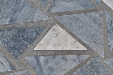 The surface of the triangular marble tiles. In the center of the white triangle, on the edges of the gray triangles. The triangles are arranged in a chaotic order. Background, texture, backdrop.