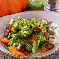 Closeup photo of pumpkin salad with asparagus, lettuce, dried tomatoes and cheese