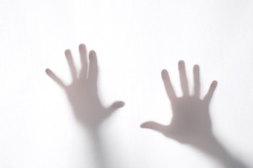 shadow or silhouette of two man's hands touching a white fabric from behind  in transparncy with copy space for your text