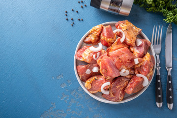 Juicy marinated pork  with spices and onion on a plate. Top view. Copy space