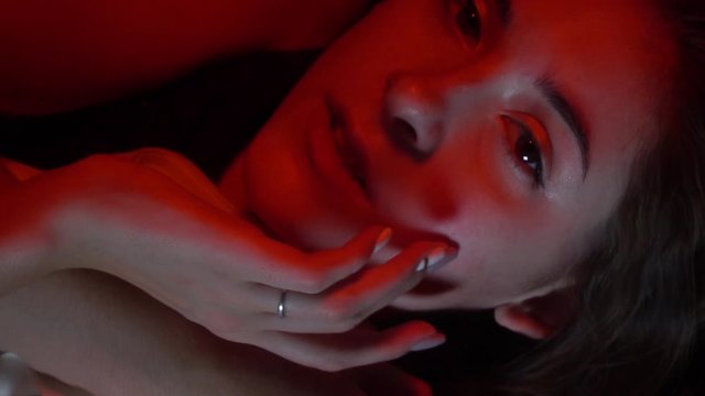 Young model is posing from underwater in red lighting, close up