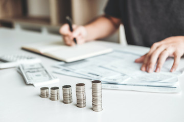 Man using calculator Accounting Calculating Cost Economic bills with money stack step growing growth saving money in home , finance concept