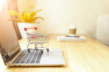 Shopping cart with laptop keyboard on wood table in office background.Easy shopping with finger...