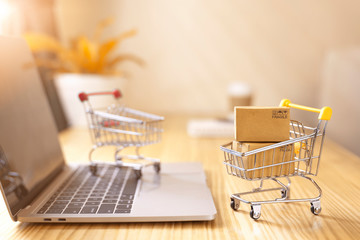 Online shopping and delivery service concept.Brown paper boxs in a shopping cart with laptop keyboard on wood table in office background.Easy shopping with finger tips for consumers.