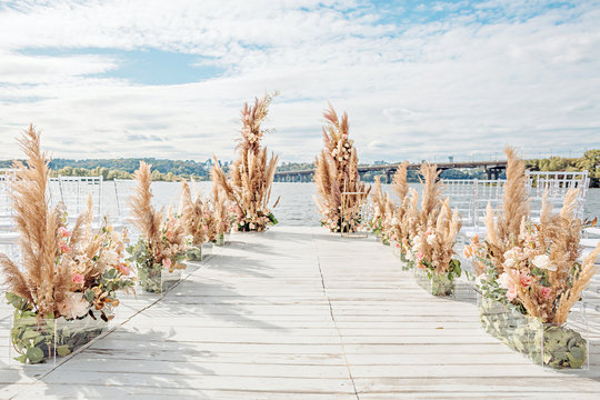 Wedding by the river. Beach wedding venue. Wooden stage with floral decorations arch
