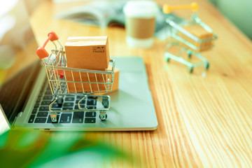Brown paper boxs in a shopping cart with laptop keyboard on wood table in office background.Easy...