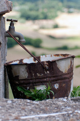 scarcity of water. ecology concept. rusty bucket in an old vintage outdoor faucet without water.