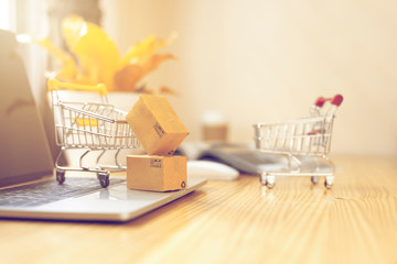 Brown paper boxs and a shopping cart with laptop keyboard on wood table in office background.Easy...