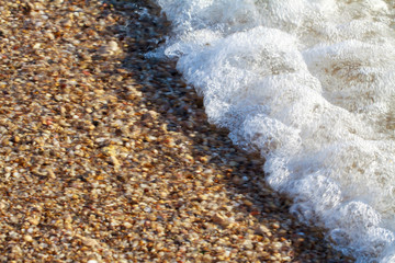 sea pebbles colored granite on the beach background stones. The shore of the beach with sand and pebbles washed by the waves of the sea.