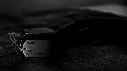 Blank military dog tags and a gun on abandoned rusty metal plate. - Memories and sacrifices concept.