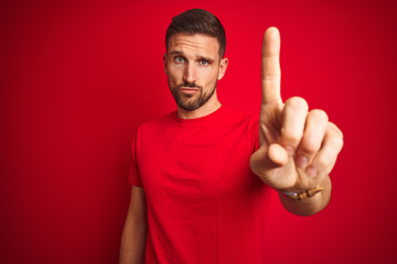 Young handsome man wearing casual t-shirt over red isolated background Pointing with finger up and...