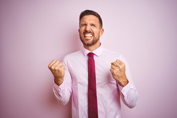 Business man wearing tie and elegant shirt over pink isolated background very happy and excited doing winner gesture with arms raised, smiling and screaming for success. Celebration concept.
