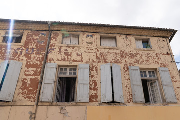 Old weathered house peeling paint open windows