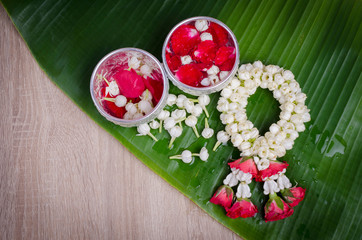 Jasmine and roses in silver bowl on leaves of banana and wood background ,Songkran festival in Thailand