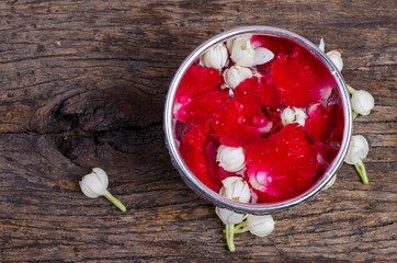 Water in water dipper with colorful flowers pedestal On an old wood background for Songkran festival, Thailand,Vintage