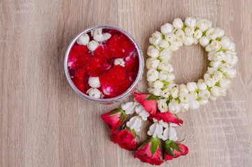 Water in water dipper with colorful flowers pedestal On an old wood background for Songkran festival, Thailand,Vintage
