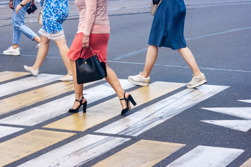 legs of young pedestrians walking on the crosswalk