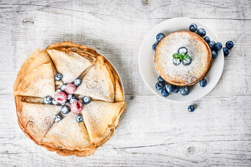 Top view of fresh baked homemade pancakes. Pancakes with blueberries on white rustic table. Thin flat cake with forest fruits.
