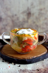 Hot soup with vegetables and meat in a beautiful transparent plate on a gray background