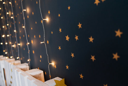 Cut and pasted gold stars on a dark wall of kids room with lights. Baby room interior concept. Handmade decoration with stickers of baby room.