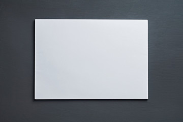 Single stack of blank white paper sheets lies on dark concrete table on workplace of secretary, director, boss or other worker of company. Space for text. Top view. Close-up