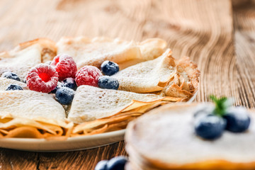 Fresh pancakes on wooden table with forest fruits like blueberries and raspberries. Pancakes with forest fruits.