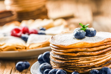Pancakes with forest fruits. Blueberries on heap of pancakes with mint leaf.