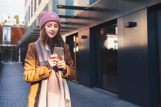 Young woman walking down street and shooting video for social network. Female using smartphone outdoors. Girl holding mobile phone