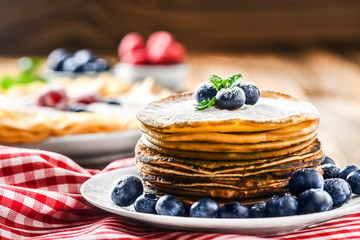 Pancakes and forest fruits. Blueberries, raspberries and green mint leaf. Pancakes on wooden table.