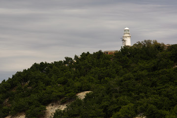 Fototapeta na wymiar Lighthouse on top of a wooded hill