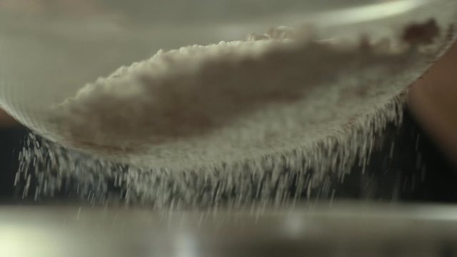 Close up slow motion of sifting flour and coco powder.