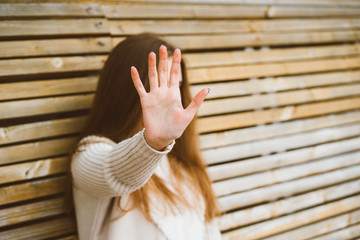 Woman with long hair reaches forward, shielding her face from camera. Concept of privacy, personal...