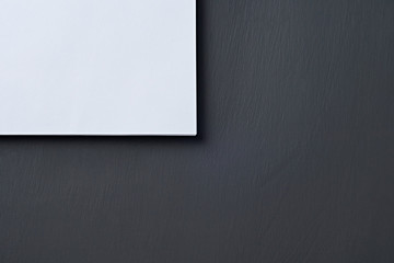 Obraz premium Corner of heap of blank white paper sheets lies on dark concrete table on workplace of secretary, director, boss or other worker of company. Space for text. Top view
