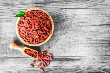 Goji fruits in bowl from top view. Goji in wooden scoop.