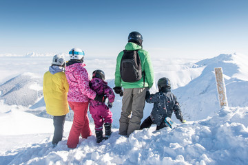 Snowboarders family looking at mountain peaks at ski resort