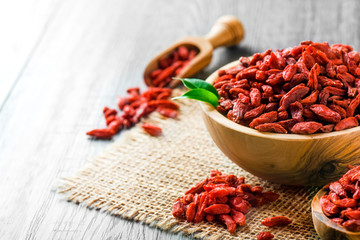 Goji fresh fruits seeds in wooden bowl with scoop ful of goji. Goji on table.