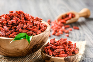 Goji fresh fruits seeds in wooden bowl with scoop ful of goji. Goji on table.