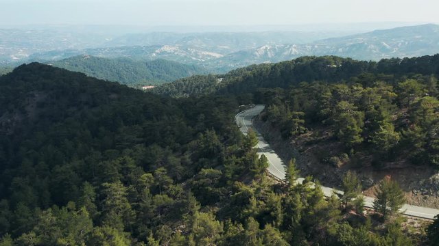 Drone aerial shot of empty road in Troodos mountains, Cyprus. Huge green pine forest covers mountain slopes